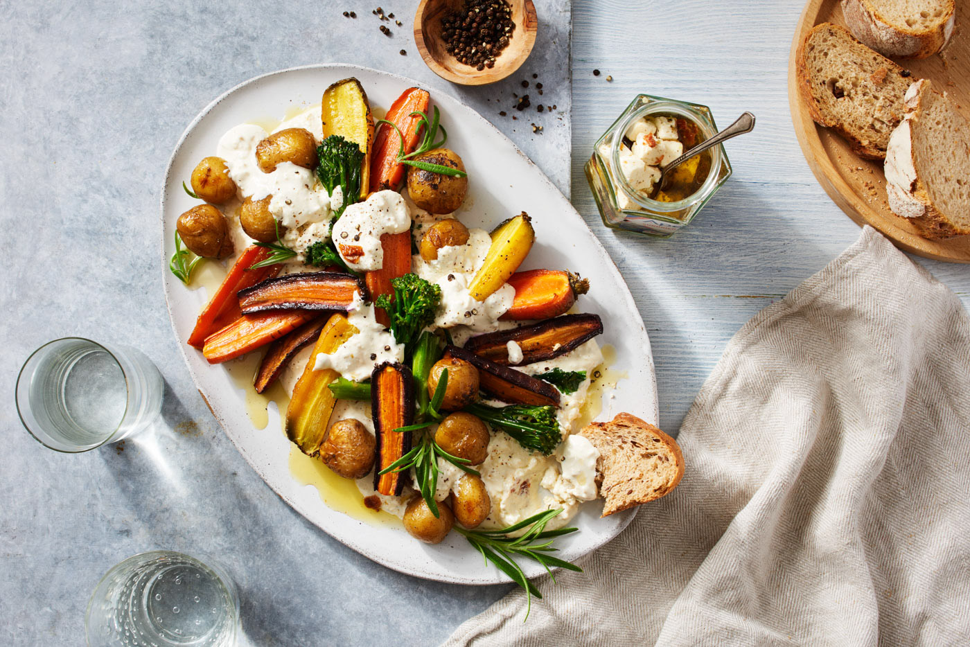 Paahdettuja kasviksia burrata-juustolla ja tuoretta leipää lautasella.