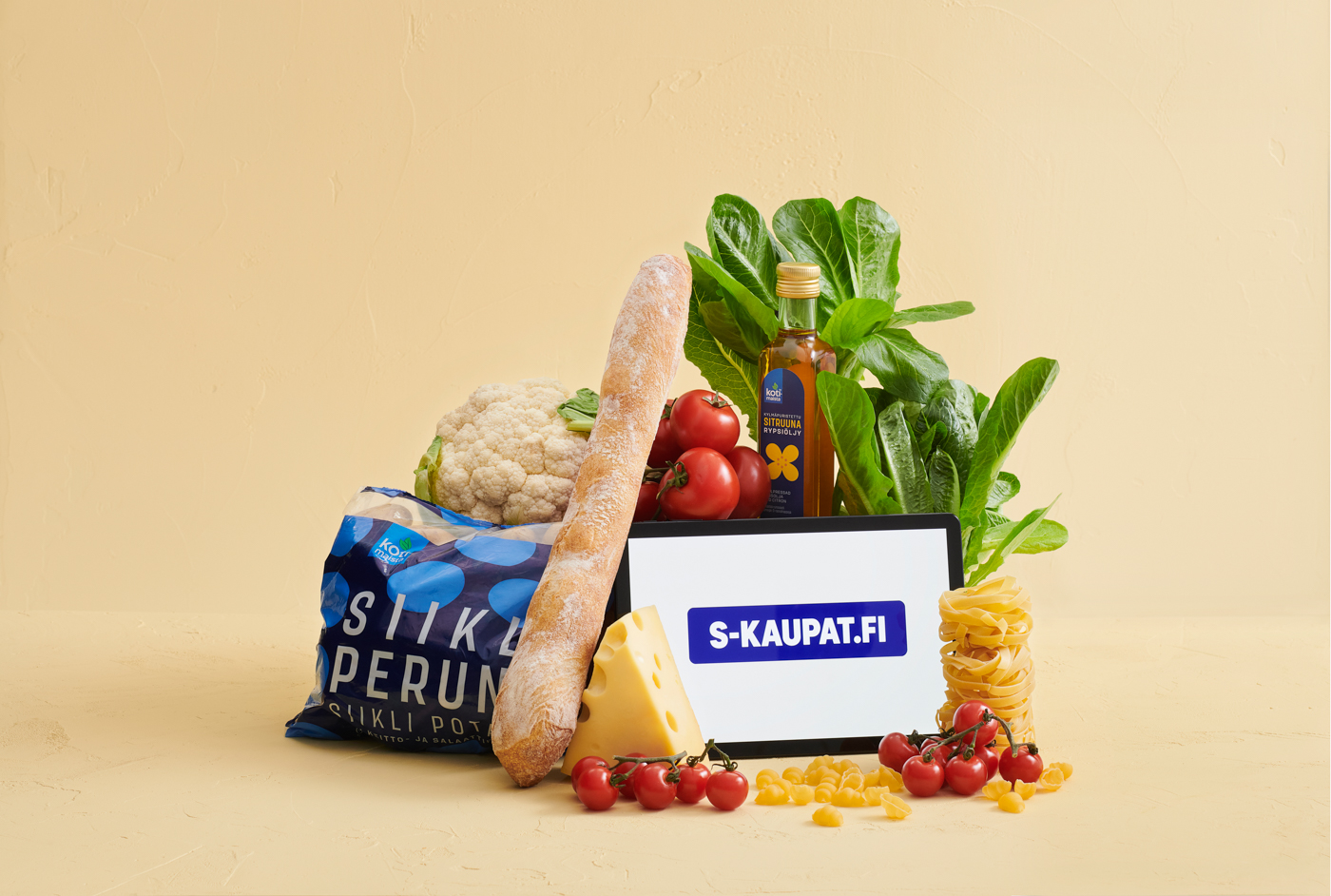 Ruokakori täynnä leipää, kukkakaalia, tomaatteja, juustoa, pastaa ja öljyä - S-Kaupat.fi näkyy tabletissa.