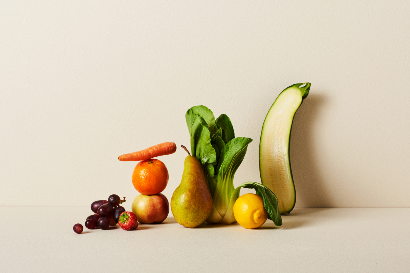 hedelmien ja vihannesten asetelma: porkkana, appelsiini, omena, päärynä, bok choy, sitruuna, kurkku ja viinirypäleet.